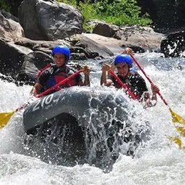 A couple rafting white water rapids with an inflatable kayak