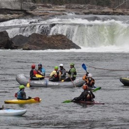 Group of people with rafts and canoes on white water rapids