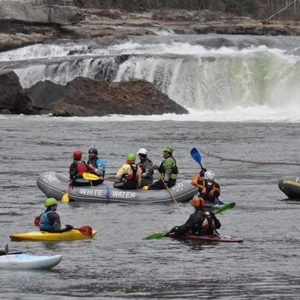 Group of people with rafts and canoes on white water rapids