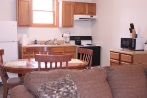 Full kitchen in our suite Suite full kitchen. The kitchen contains a stove with oven, a refrigerator, circular table fitting four people, and a microwave.